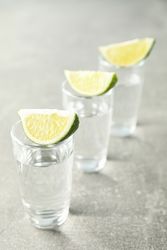 Tequila shots with lime slices on grey background