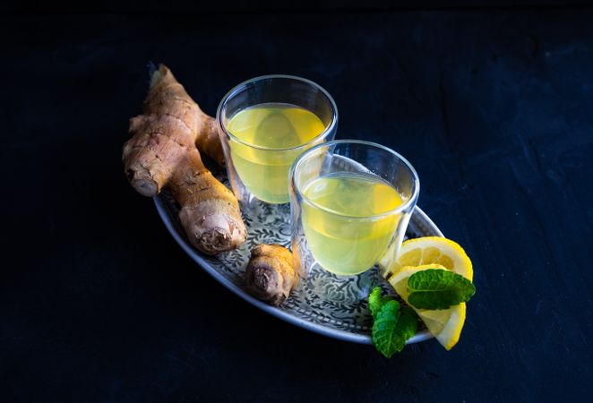 Silver tray with two yellow detox drinks with ginger and lemon