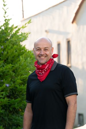 Portrait of handsome man wearing red bandana around his neck smiling and looking at camera