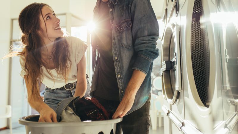 Man and woman putting clothes in a washing machine together