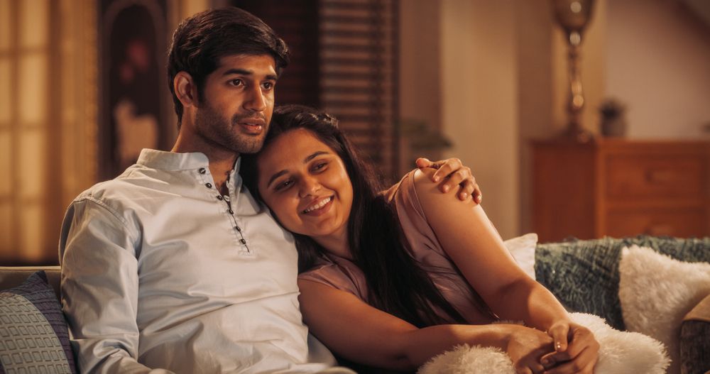 Movie Night: Young Couple Relaxing on the Couch, watching Exciting Movie on TV.