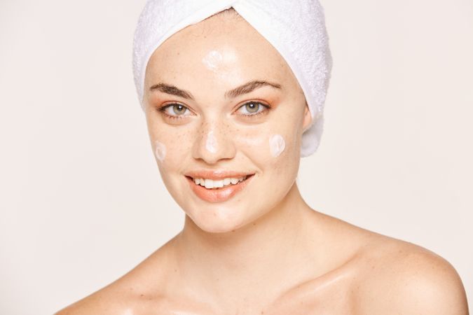 Delighted female with radiant skin applying cream