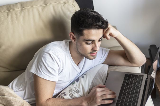 Young man relaxing on couch while using laptop