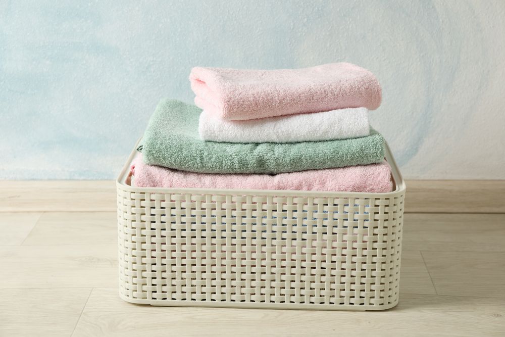 Basket with clean laundry on textured floor, space for text