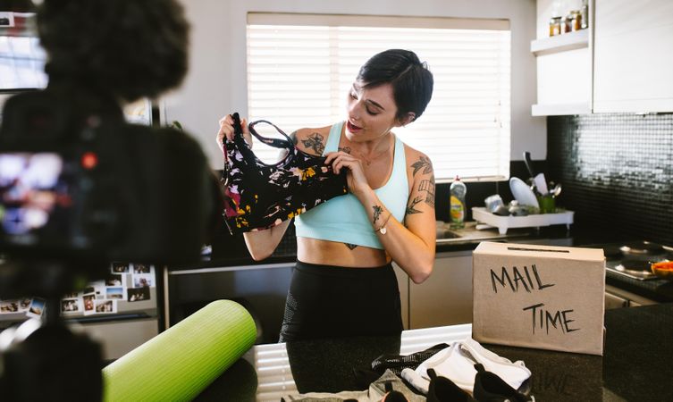 Female vlogging about women's sportswear and filming herself at home on digital camera