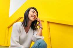 Smiling Asian woman talking on the phone in a coworking