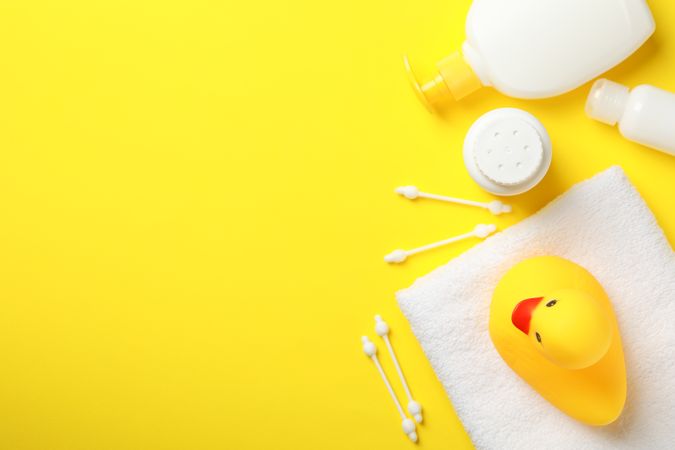 Baby hygiene accessories on yellow background, top view and space for text