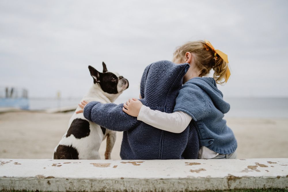 Kids hugging dog on beach