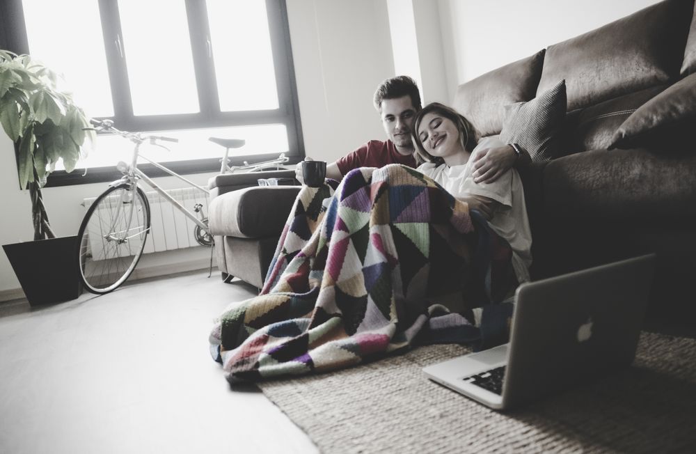 Couple wrapped in plaid watching laptop