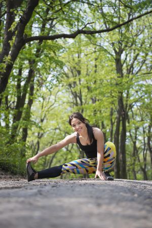 Woman smiling while stretching her leg before a run