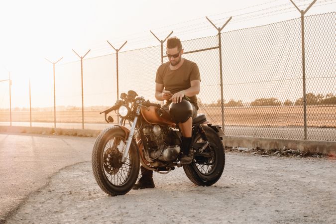 Man sitting on motorcycle and surfing mobile