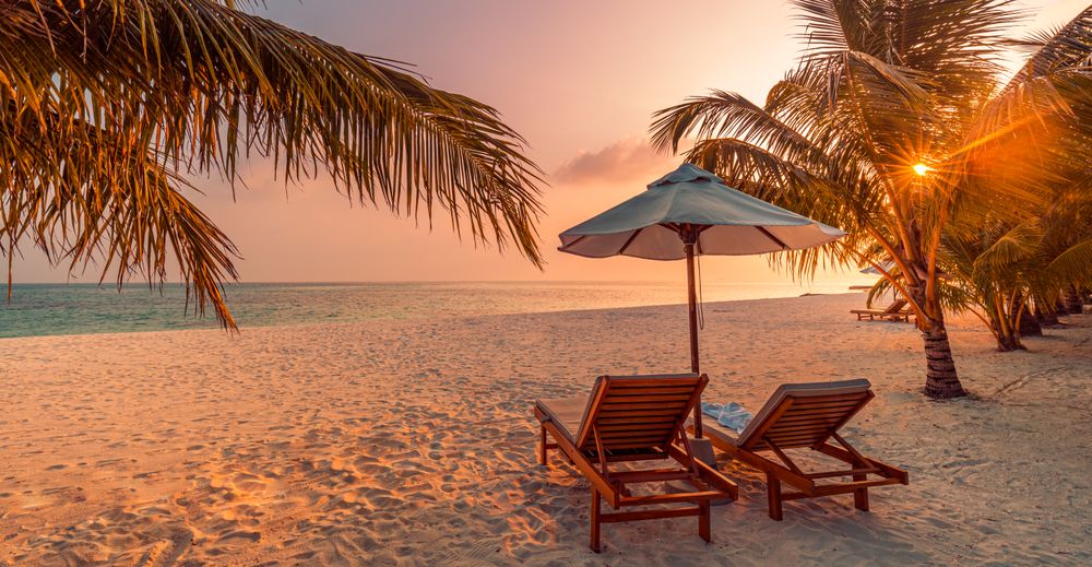 Two reclining lounge chairs on a beach, wide shot