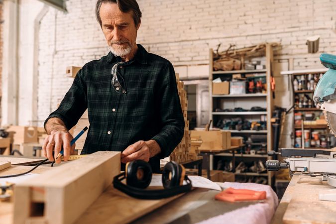 Mature male working with wood in workshop