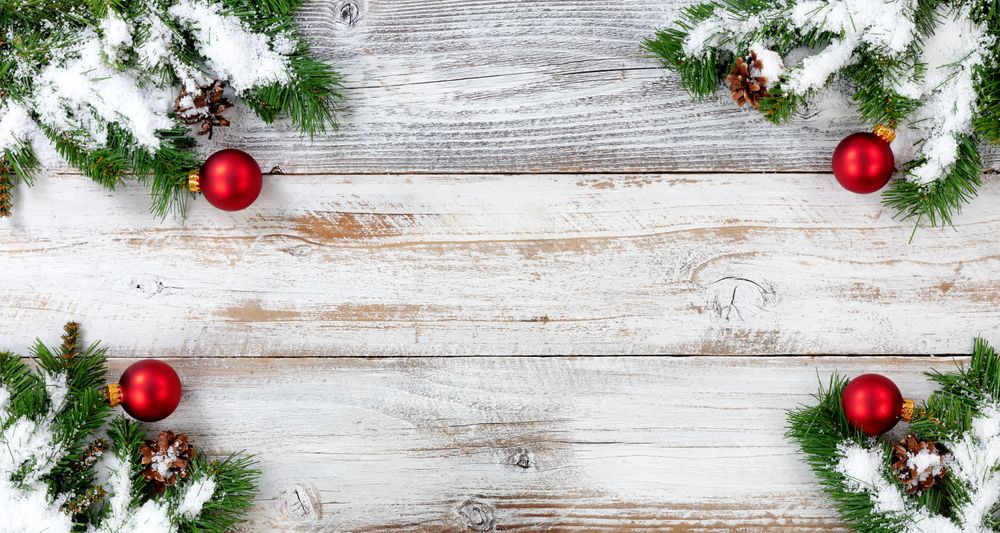 Christmas snow covered evergreen branches and red ball decorations in all corners on vintage wooden boards