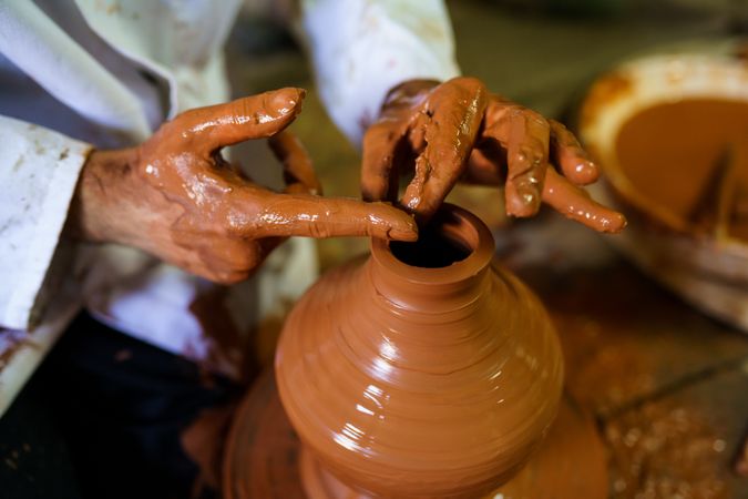Hands of person crafting vase with pottery wheel