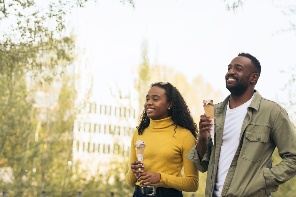 Black couple eating ice cream in a park