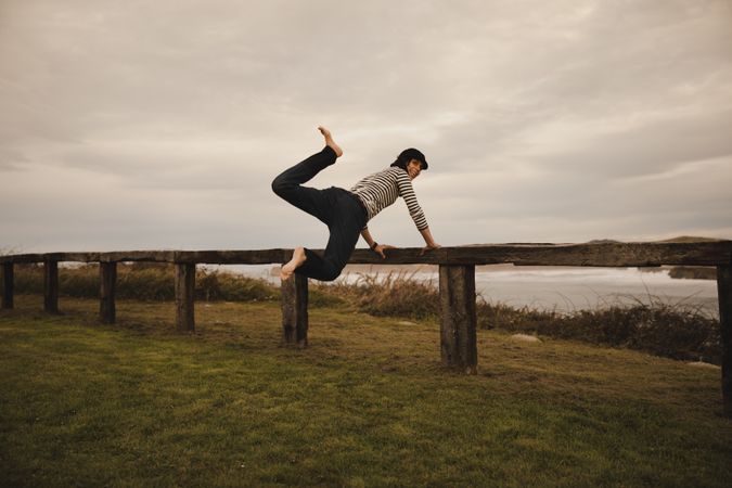 Woman jumping near bench on shore near water