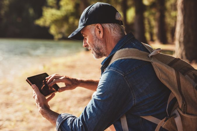 Portrait of mature male hiker using digital tablet outdoors