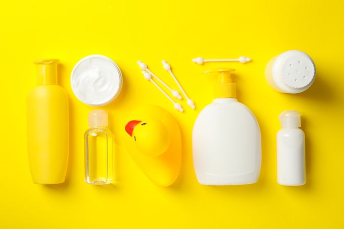 Flat lay with baby hygiene accessories on yellow background