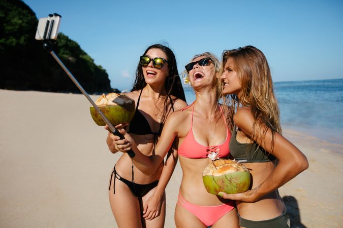 Group of friends in swimsuits taking a selfie at the beach