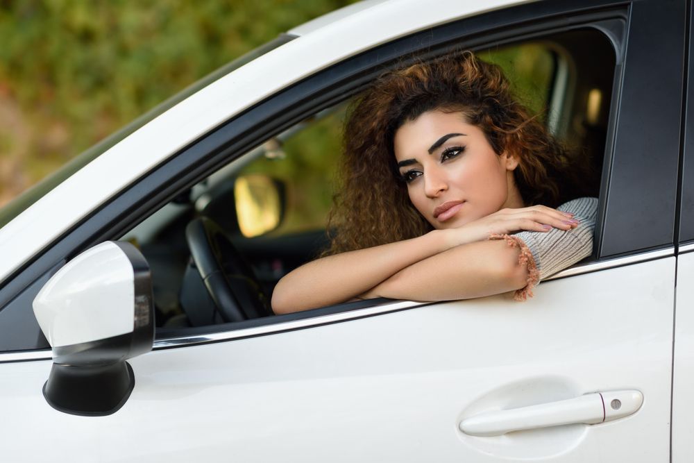 Female with curly hair leaning out driver’s window