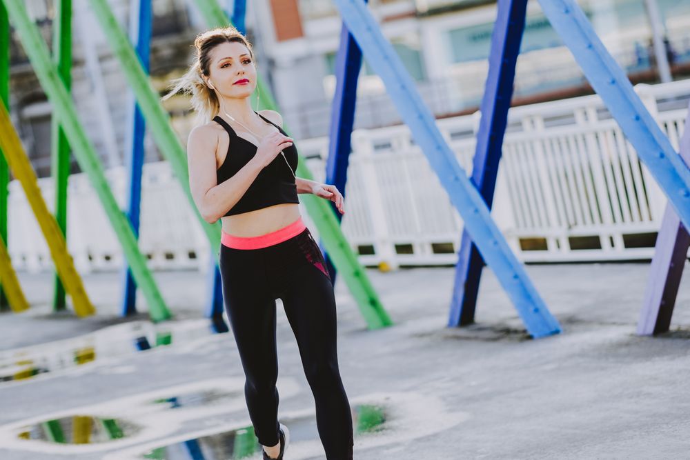 Woman with earphones running on street