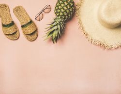 Sandals, glasses, pineapple, straw hat on pink background, with copy space