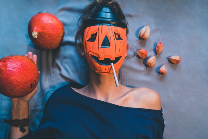 Woman in pumpkin mask with spliff