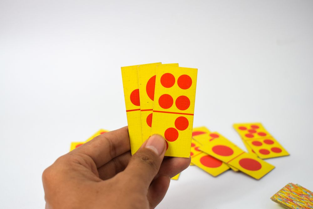 Person holding three domino cards
