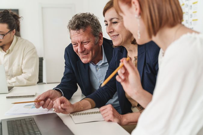 In a modern office, three colleagues focus on a laptop screen