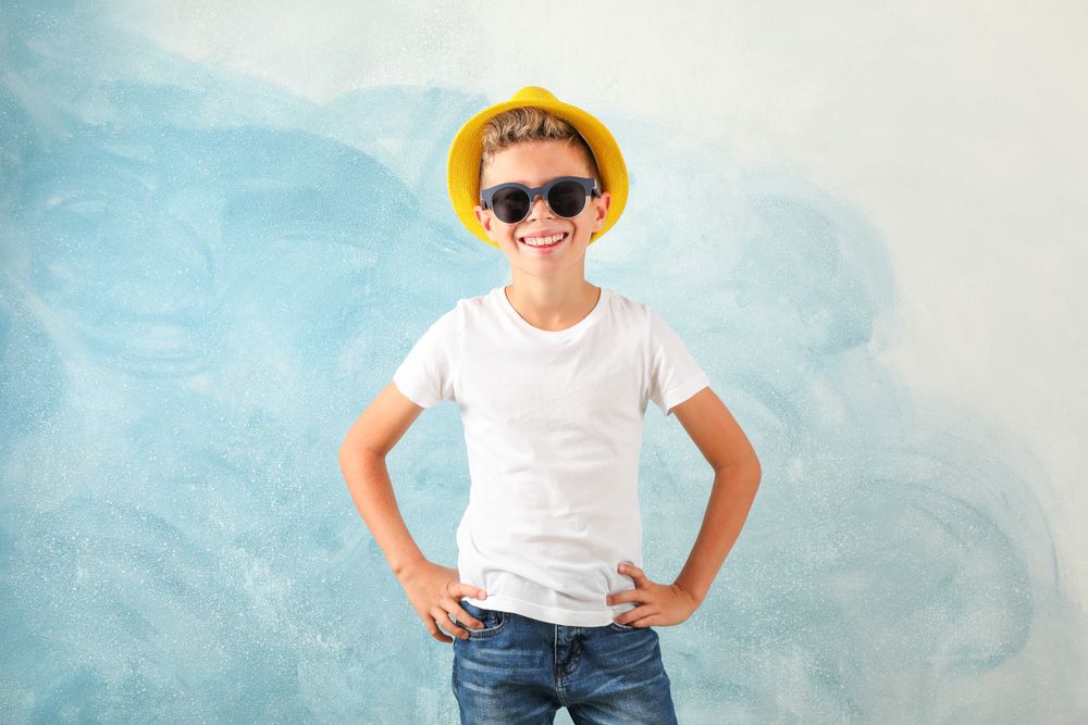 Boy with sunglasses and hat against color background, space for text