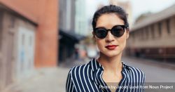 Portrait of woman wearing sunglasses walking outside on the city street 42Rqq4