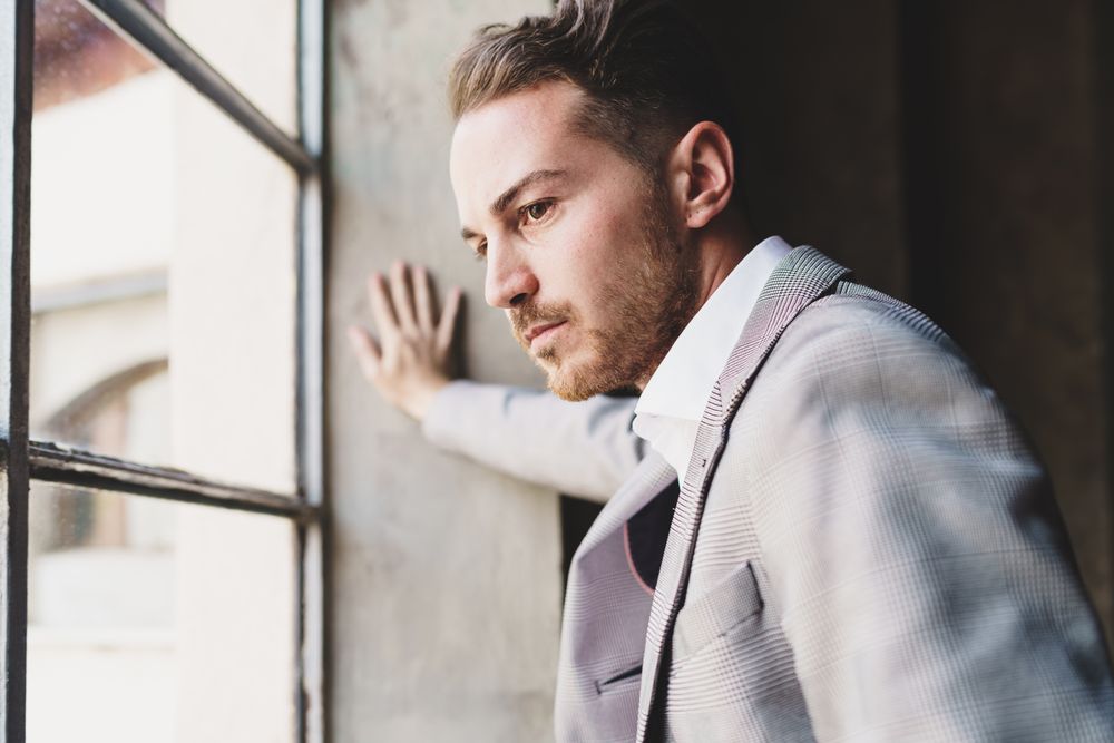 Pensive businessman from the future looks out of the window with blank stare