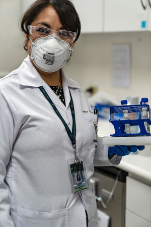 Female scientist in PPE holding a tray of samples