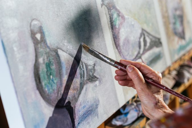 Anonymous woman painting on canvas in garden