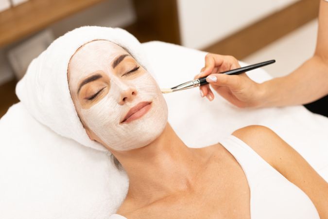 Female having a face mask professionally applied at relaxing spa