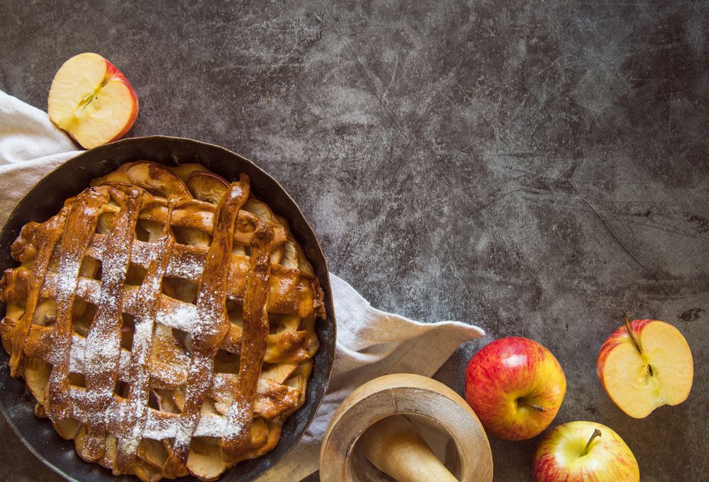 Baked apple pie on table with fruit