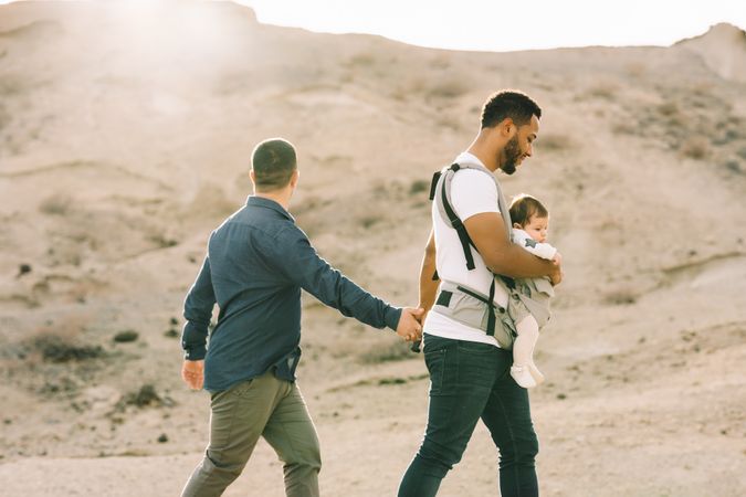 Unrecognizable diverse men walking with baby on nature
