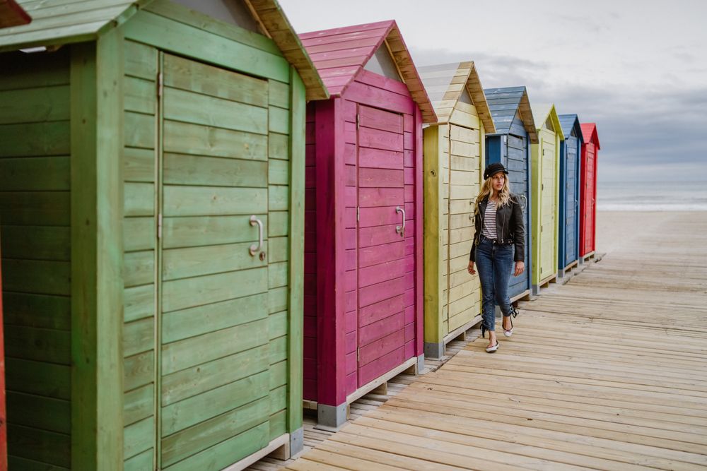Woman walking throughout wooden cabins on beach