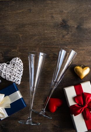 Top view of two glass champagne flutes with gifts and heart ornaments with copy space