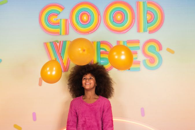 Cheerful Black girl with air balloons in studio