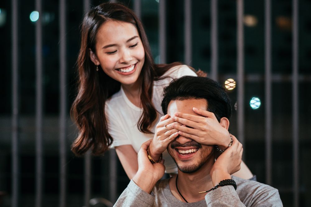 Woman closing boyfriend eyes to surprise him