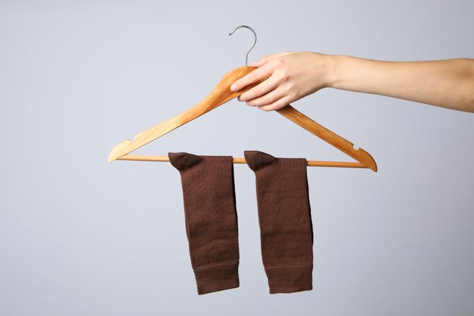 Female hand holds hanger with socks on gray background