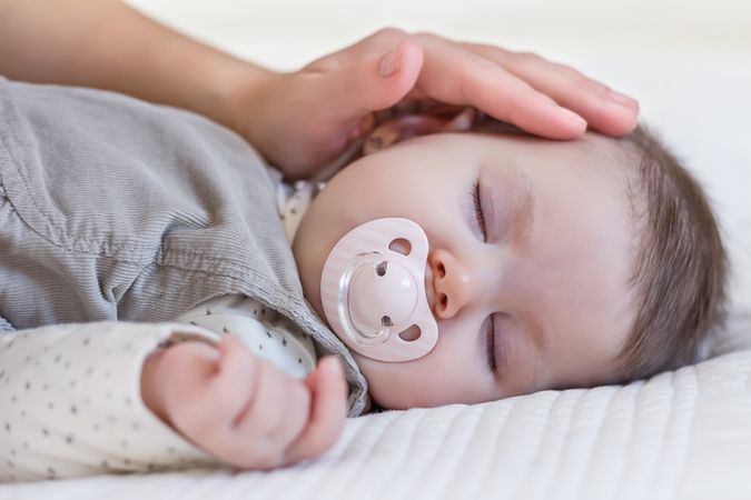 Hand of mother caressing her baby girl sleeping.