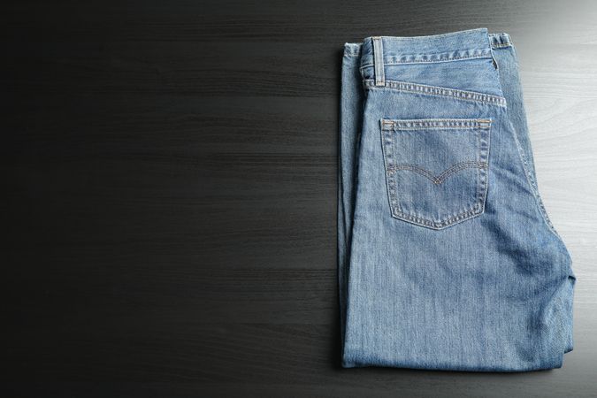 Folded jeans on table, space for text