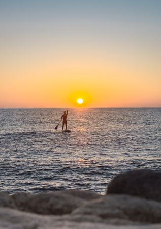 Man practicing paddle surfing with neoprene in a sunrise