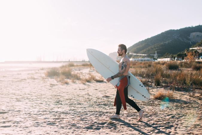 Surfer in wetsuit walking with surfboard