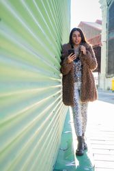 Trendy woman with smartphone near wall