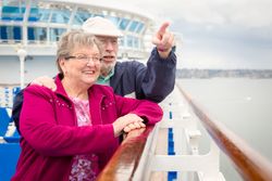 Content Older Adult Couple Enjoying The View From Their Passenger Cruise Ship Railing.