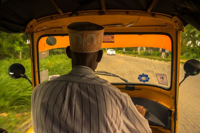 Back view of man wearing a hat driving tuk-tuk